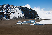 På vei opp til Reusch Crater med utsikt ned i krateret med det lille som er igjen av Furtwanglerbreen. Uhuru Peak ses i bakgrunnen, med ruta opp fra krateret.