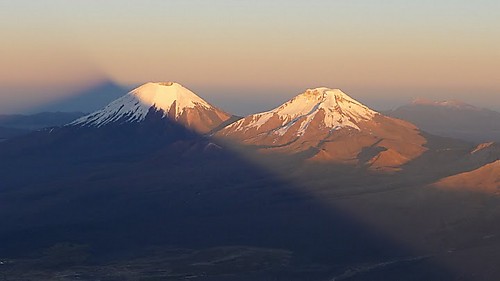 Soloppgang naer toppen av Sajama (legg merke til skyggen). Her ser man vulkanene Parinacota (6348m) and Pomerape (6282m) paa grensen til Chile