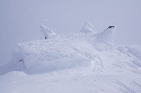 Hytten på toppen av Galdhøpiggen 2469 moh sett fra topppunktet. Dekket av mye snø.