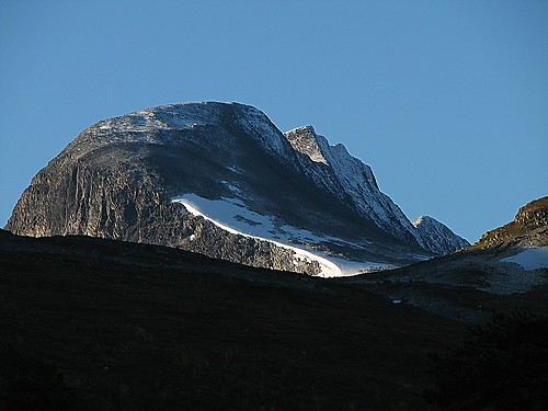 Tverrådalskyrkja (2087) zoomet inn fra Sota Sæter. Nordtoppen (1990) med den brede nordflanken, hvor vi gikk opp, midt i bildet. Litt ned igjen og mot høyre ses den horisontale eggen, som i sollyset etter hvert reiser seg bratt mot hovedtoppen. Der skulle vi opp!